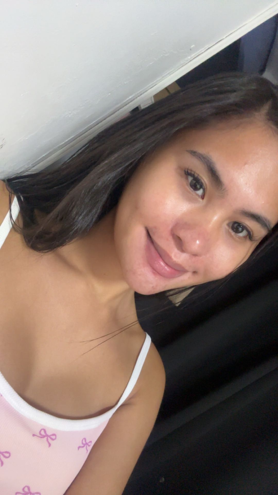 A woman from the Philippines resting on a pillow and looking at the camera