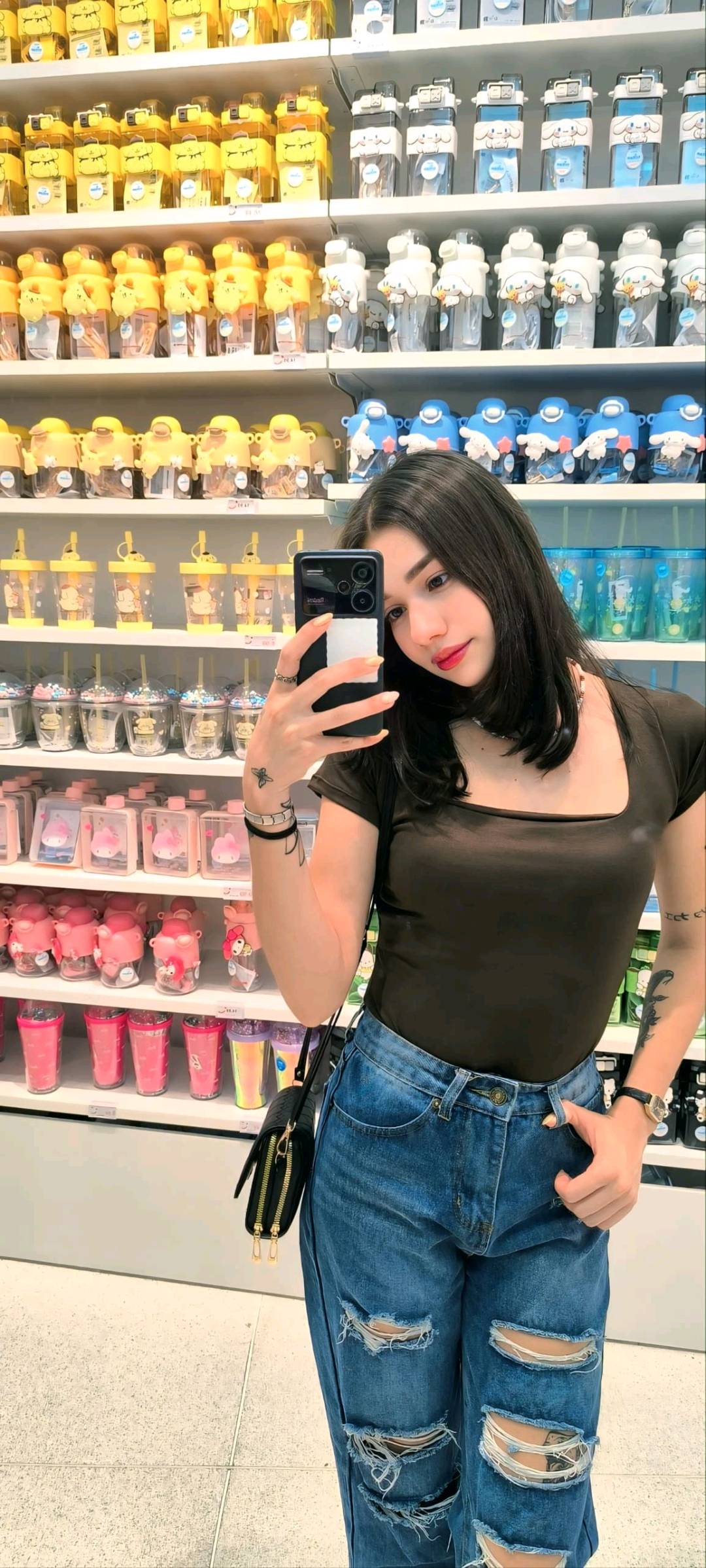 A woman from Venezuela taking a mirror selfie in a shop, phone in hand